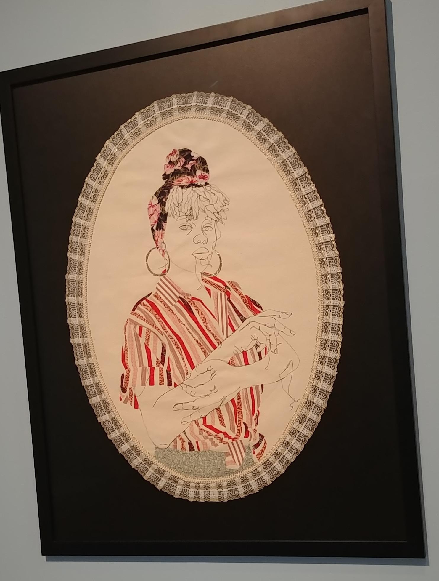 textile portrait of a Black woman in freehand stitching, with a bright pink and red applique shirt and headwrap, with a lace border around the portrait as an ornate frame