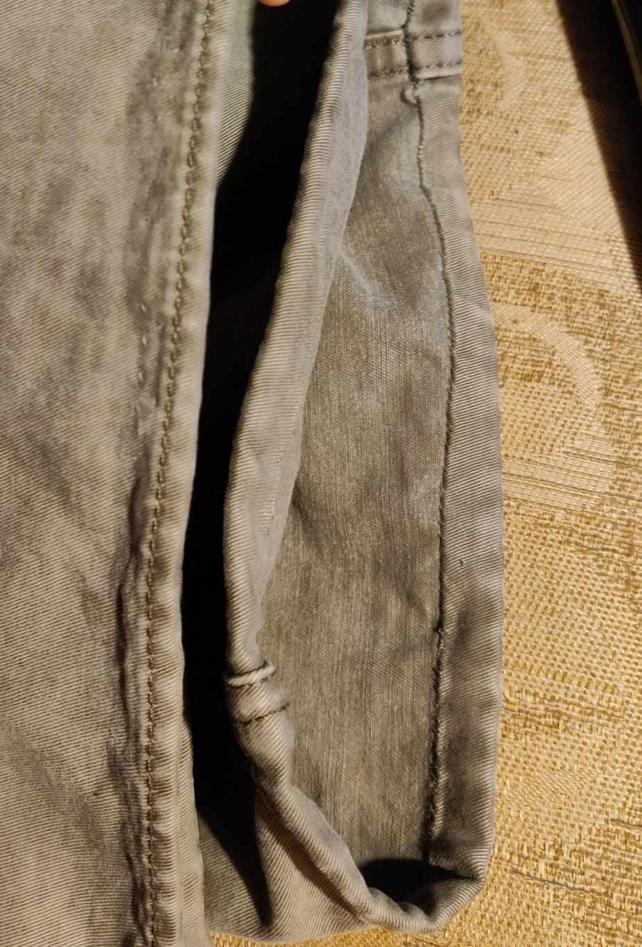 the ends of a pair of grey slacks, hemmed with nearly invisible stitches