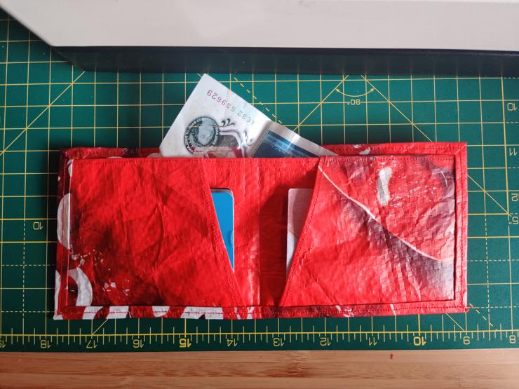 red bifold wallet sitting open on a cutting mat, some cash and cards inside